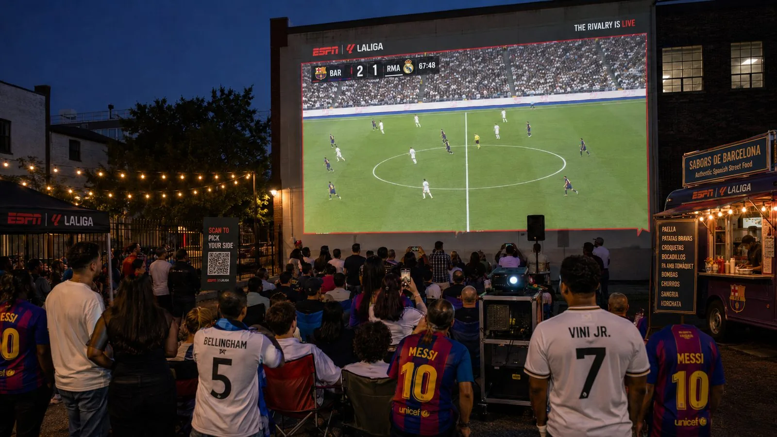 Outdoor Rivalry Watch Party with the match projected on a building wall, fans in club jerseys and a Spanish street-food truck
