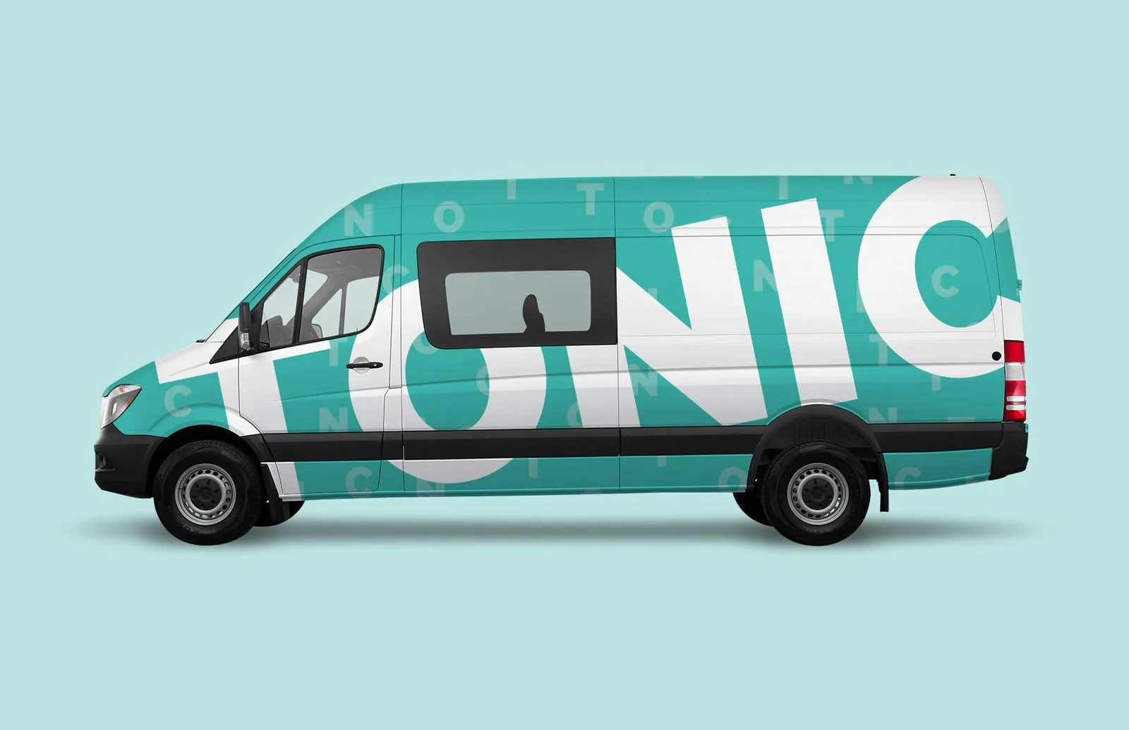 TONIC shuttle van wrapped in teal and white with an oversized wordmark running the length of the vehicle